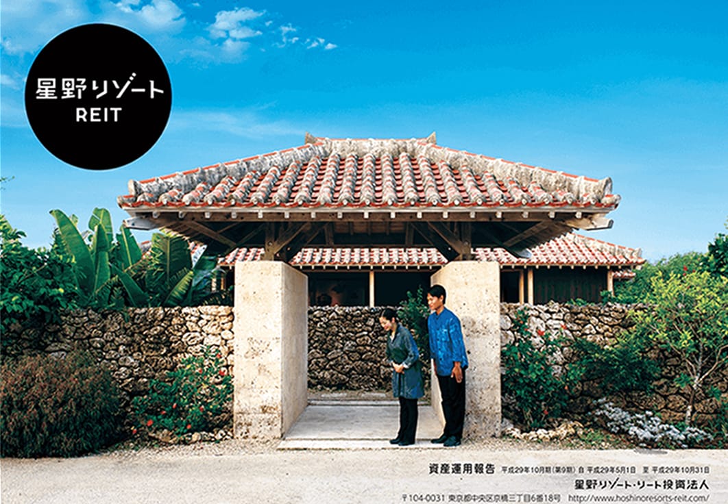 星野リゾートREITのイメージ画像。沖縄の伝統的な赤瓦屋根の建物の前で、和装の女性と男性が丁寧にお辞儀をしている。